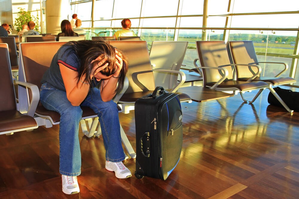 woman holding her head in frustration at airport